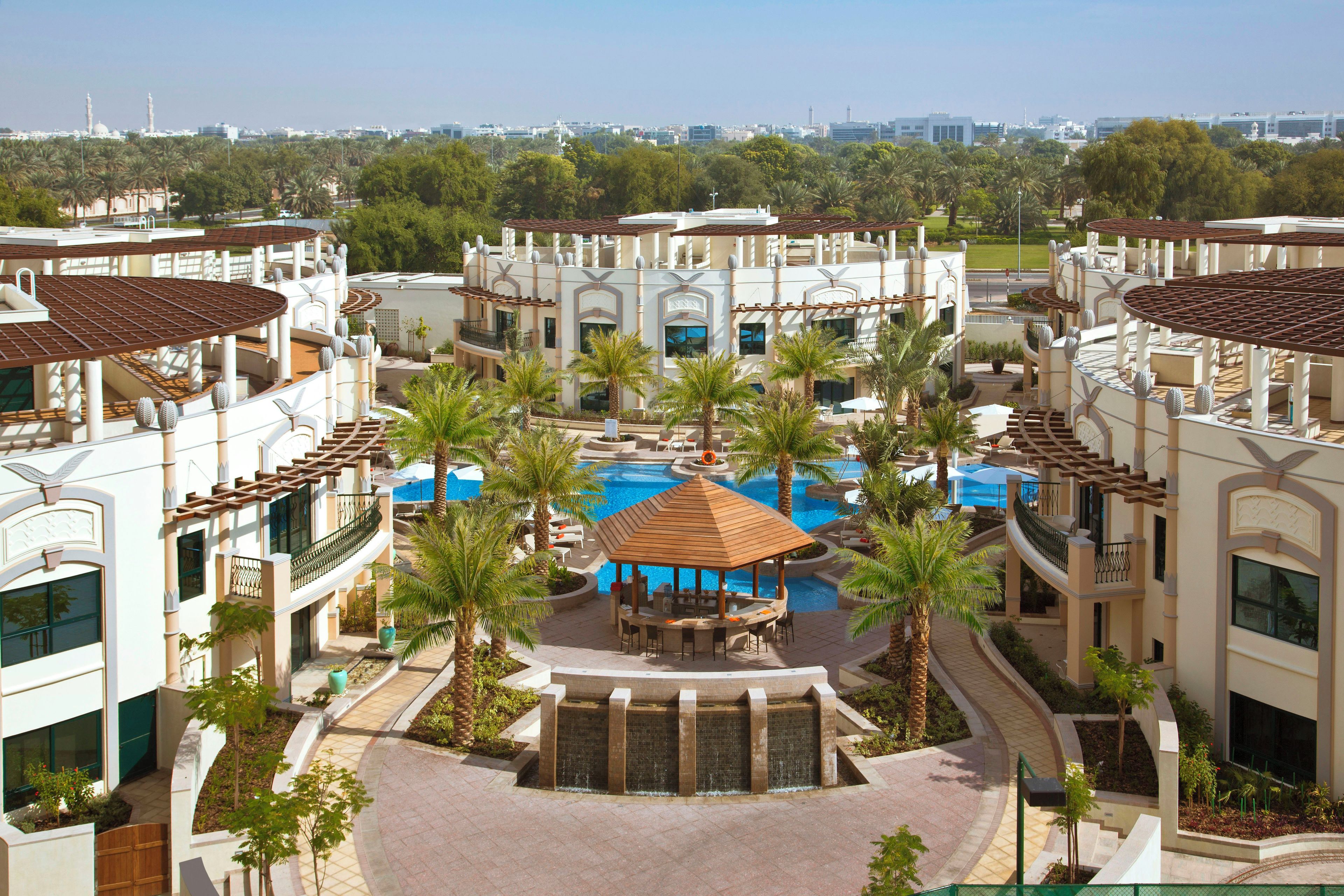 A resort with multiple buildings, a central pool area, and palm trees.