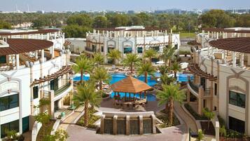 A resort with multiple buildings, a central pool area, and palm trees.