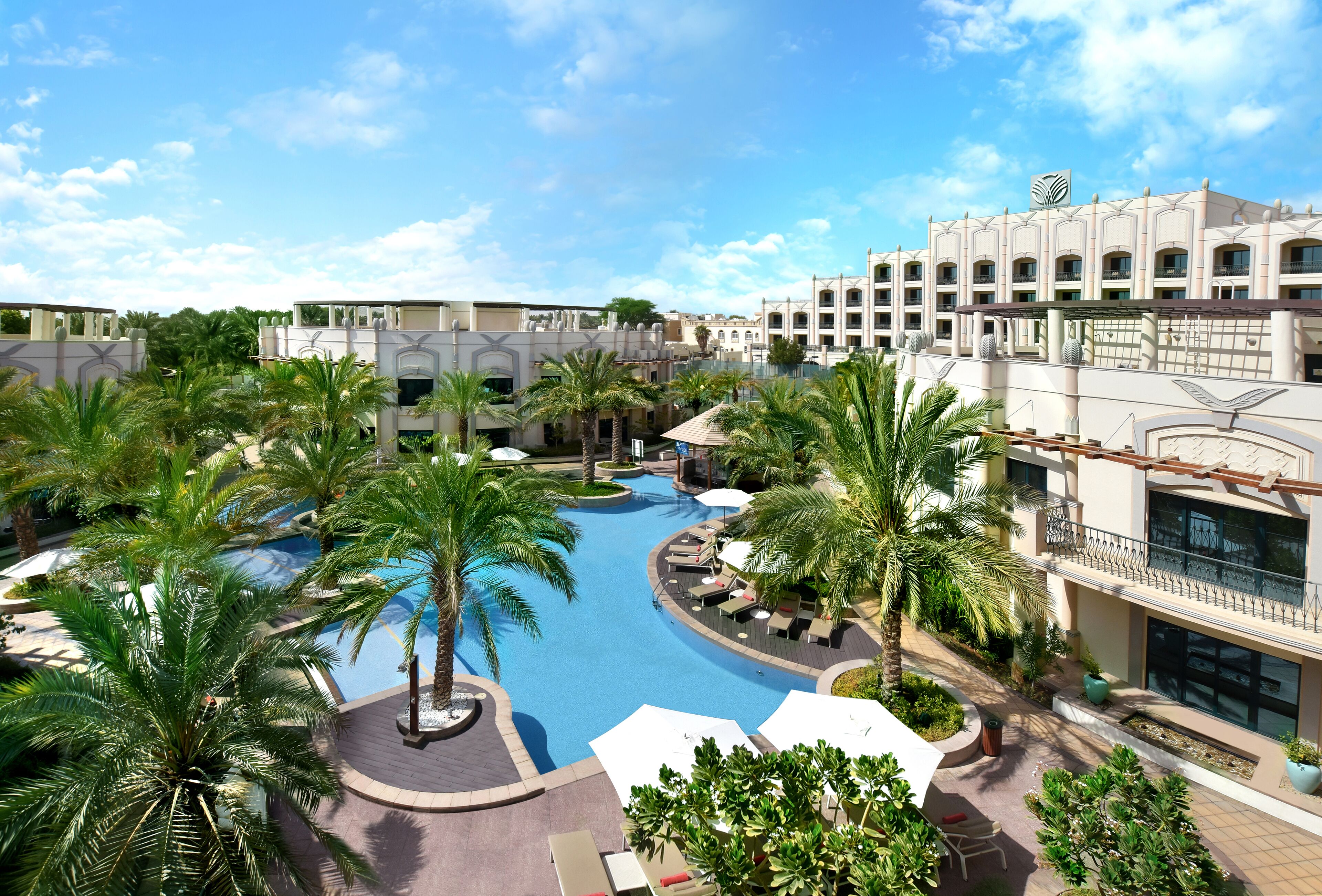 Un resort con piscina, palmeras y un edificio grande con el logotipo de una cebra.