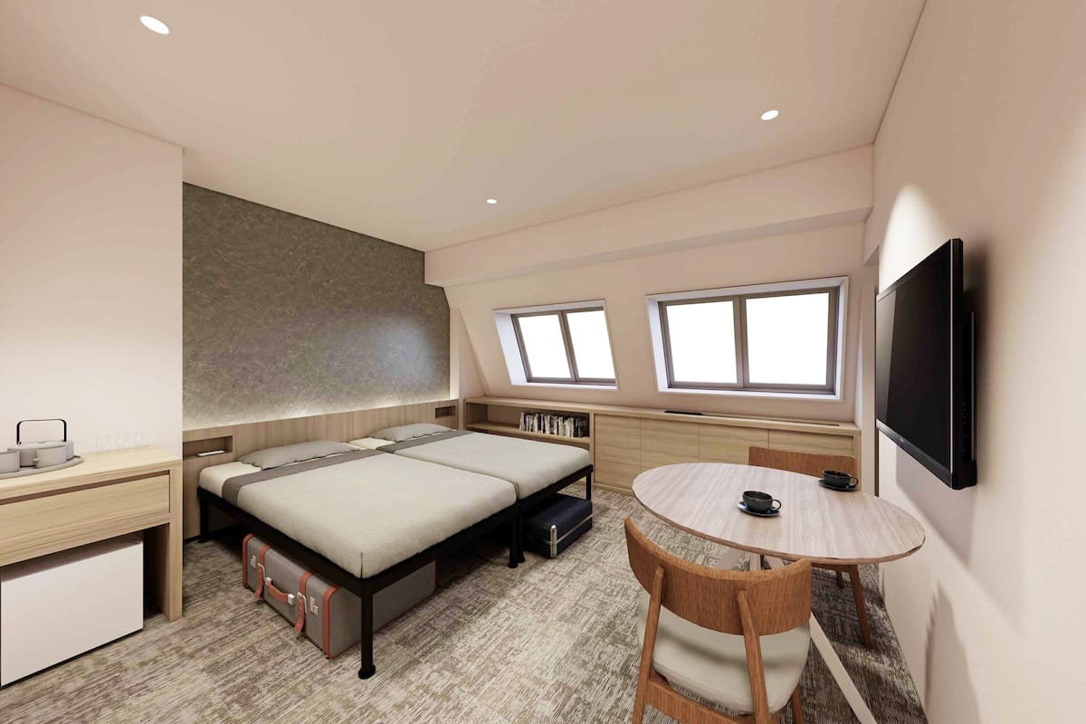 A compact hotel room with a bed, a desk, a chair, a small table, and a TV.