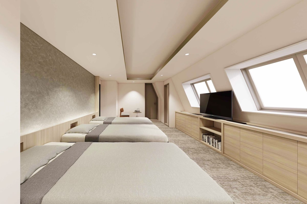 A modern hotel room with a large bed, a TV, and a window.
