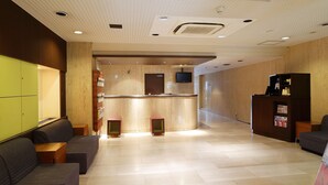 A modern lobby with a reception desk, seating area, and a large clock on the wall. - the b sangenjaya (Tokyo)