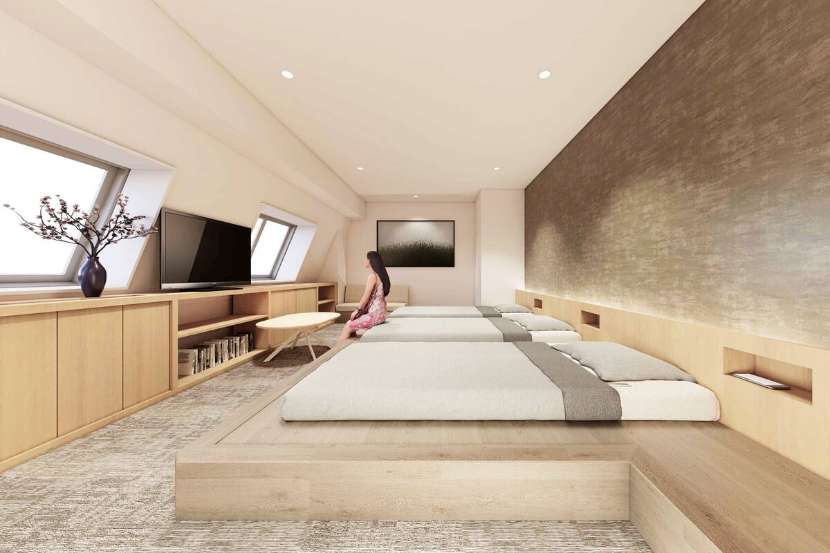 A modern bedroom with a sofa bed, a flat-screen TV, a bookshelf, and a large window.