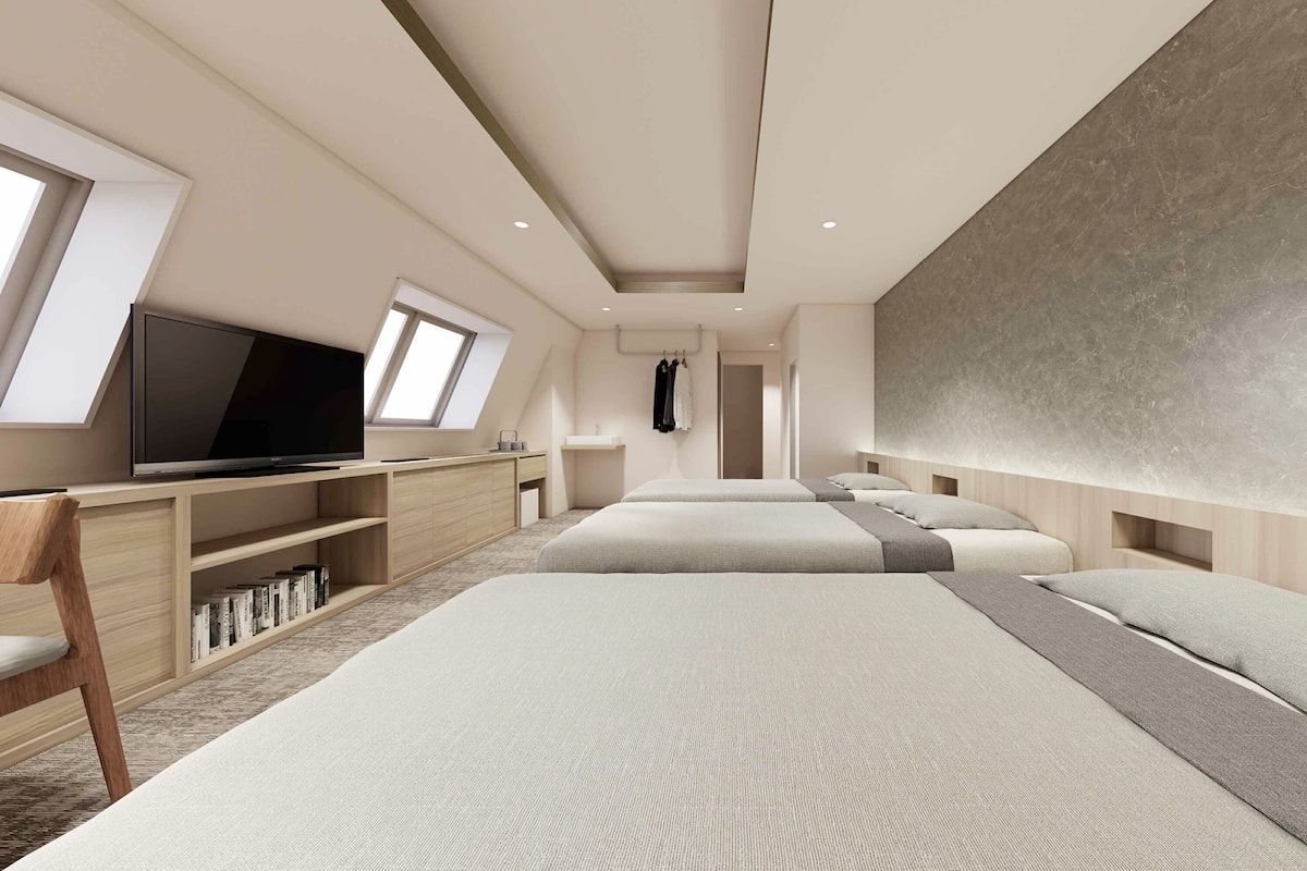 A modern hotel room with a large bed, a TV, a desk, and a wardrobe.