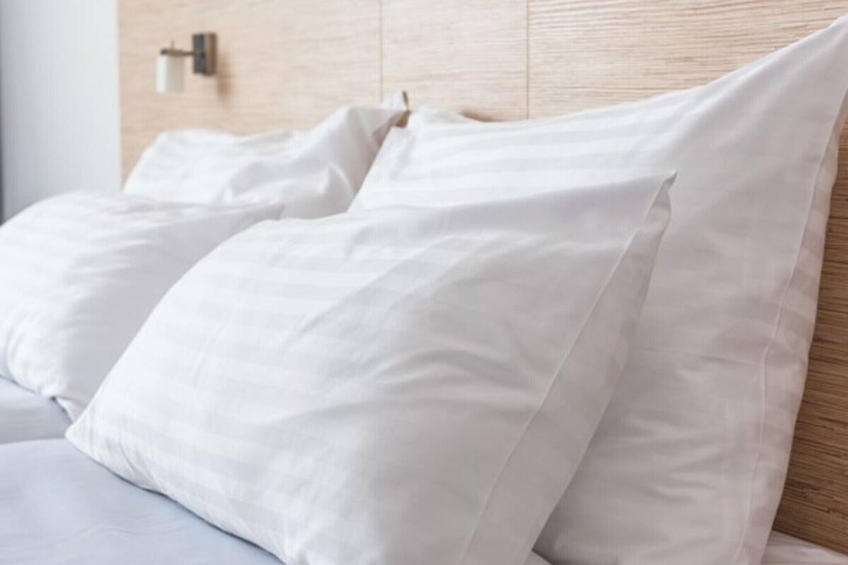 A bed with white bedding and a wooden headboard.