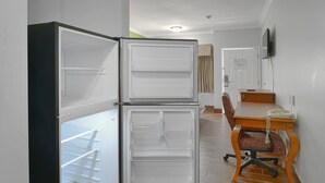 Une cuisine de taille réduite avec deux réfrigérateurs, une table à manger en bois et une chaise.