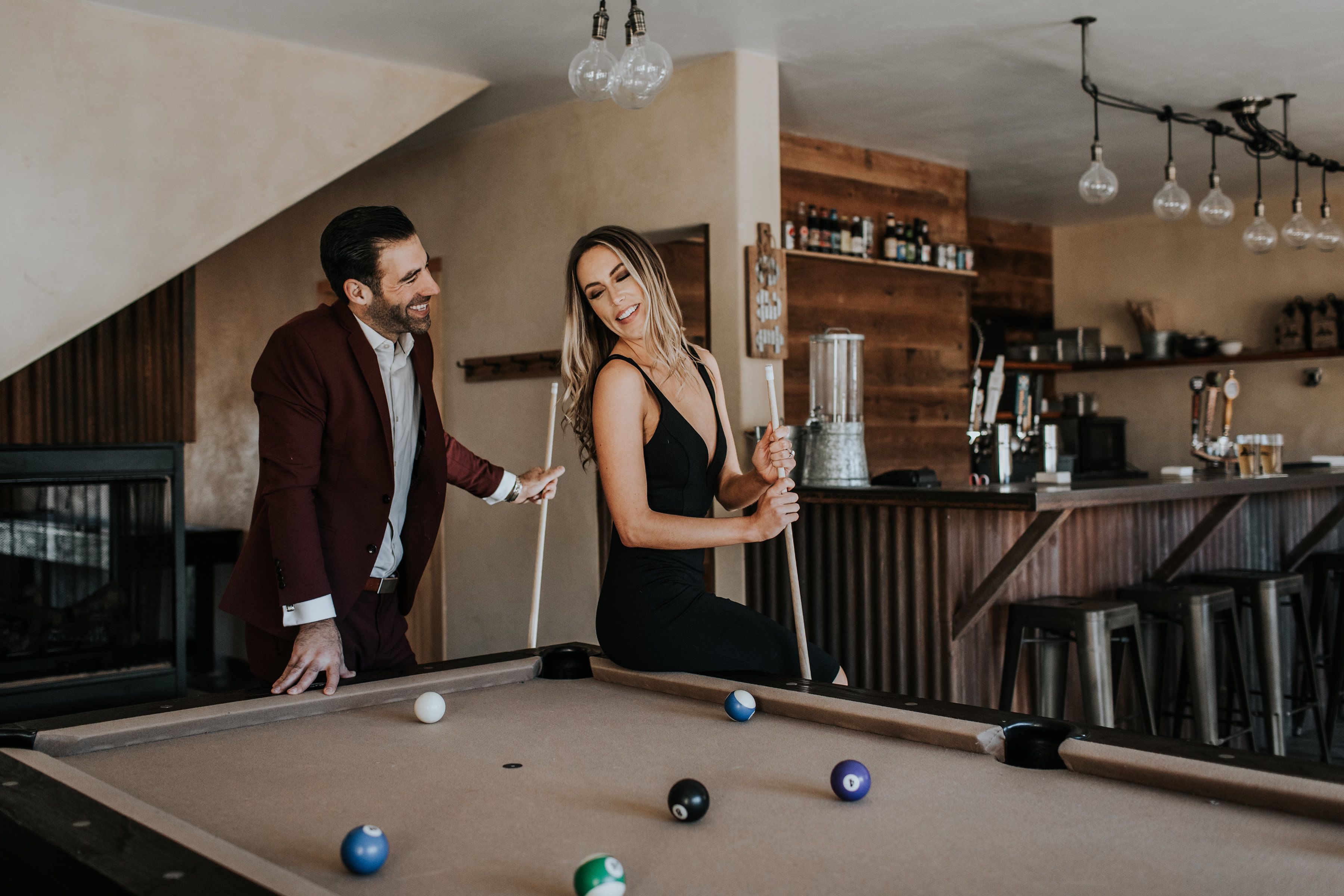 A pool table with balls, a bar area with stools, and a wooden interior.