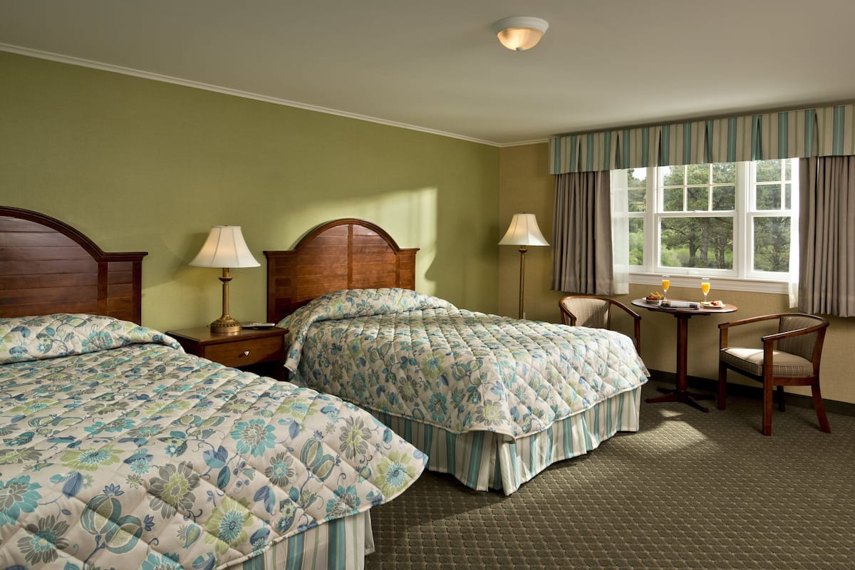 A hotel room with two beds, a desk, and a chair.