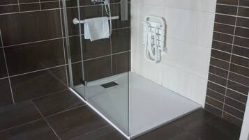 A modern bathroom with a glass shower enclosure, white tiled walls, and a white towel rack.