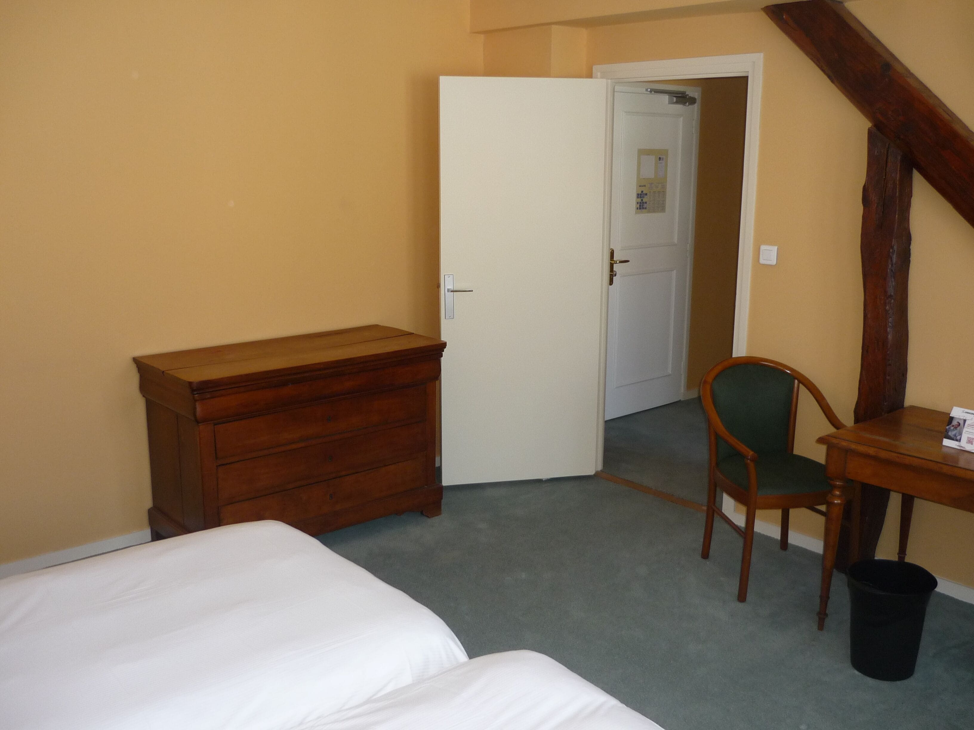 Un dormitorio con cómoda de madera, cama individual, silla y escritorio.