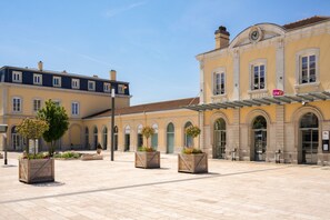 A spacious courtyard with a café named "Carrefour en Bresse" and a clock tower.