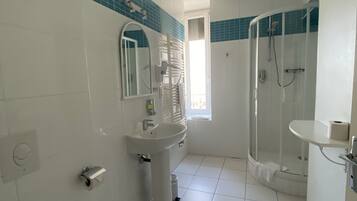 Un baño con inodoro, lavamanos y zona de ducha.