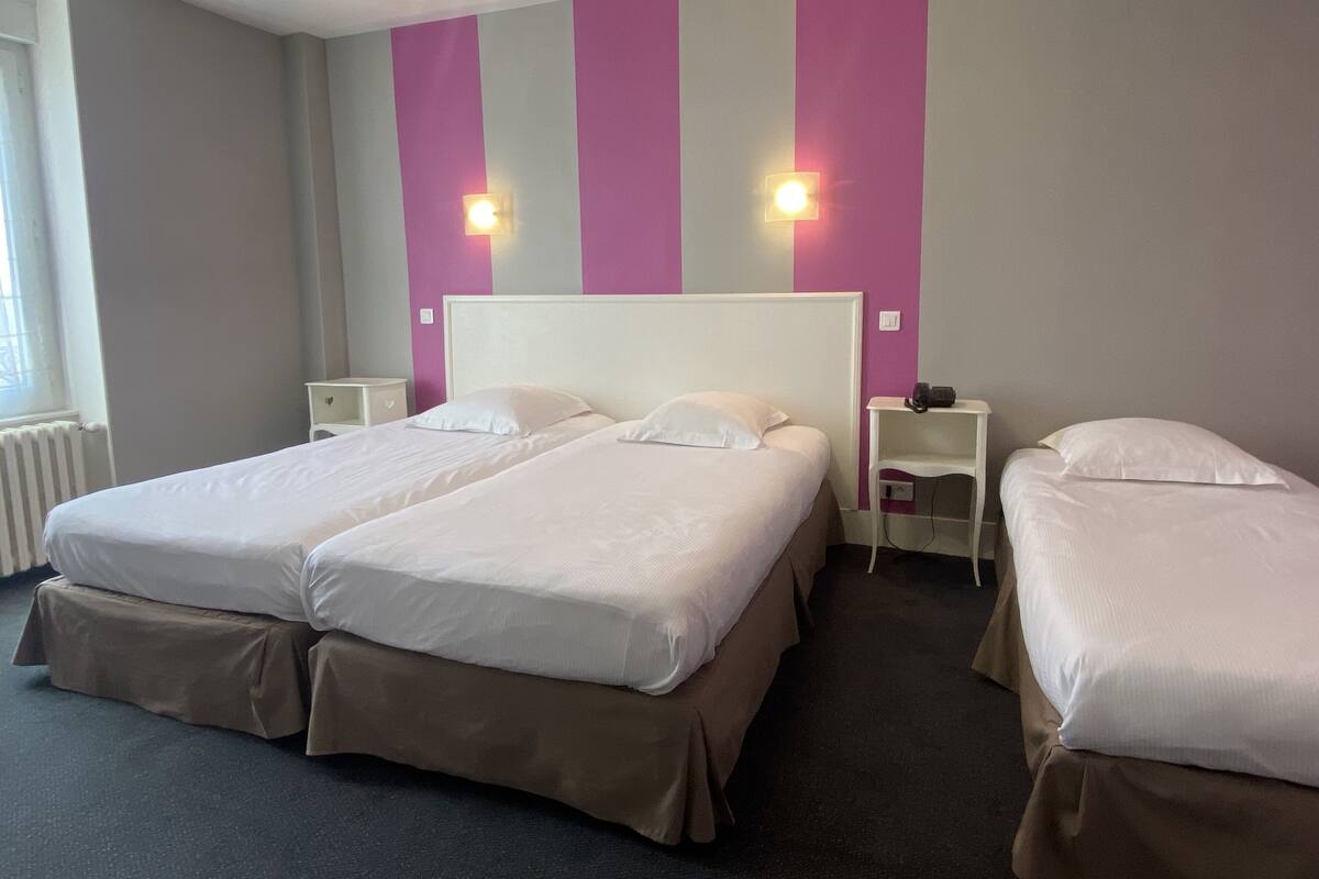 A hotel room with two beds, a window, and a wall with vertical stripes.