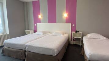 Une chambre d’hôtel avec deux lits, une fenêtre et un mur à rayures verticales.