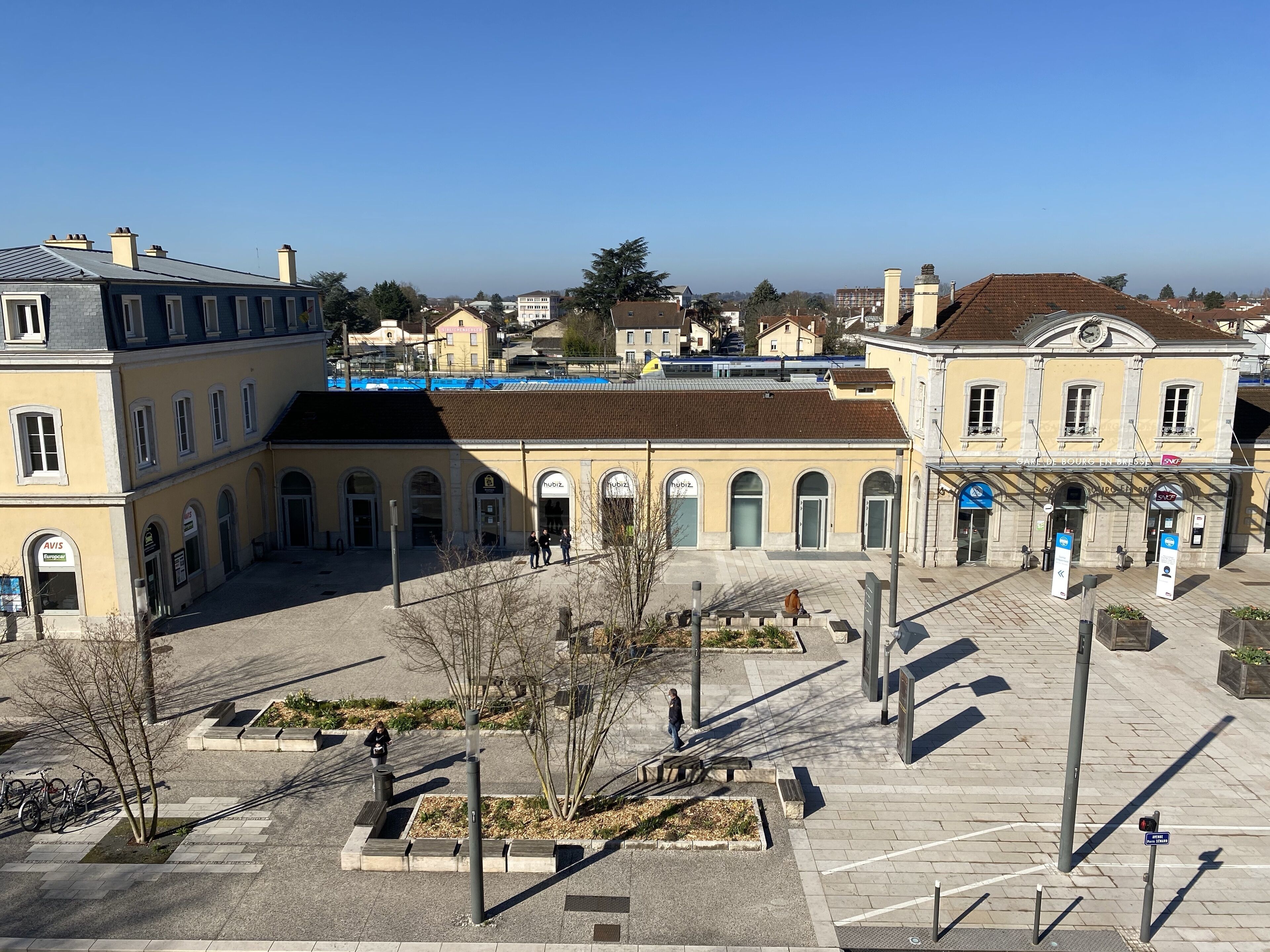 A courtyard with buildings, a clock tower, and a clear sky.