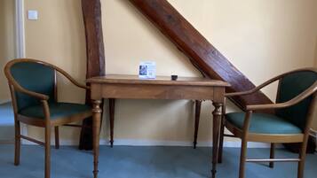A room with a wooden table and two chairs with green upholstery.