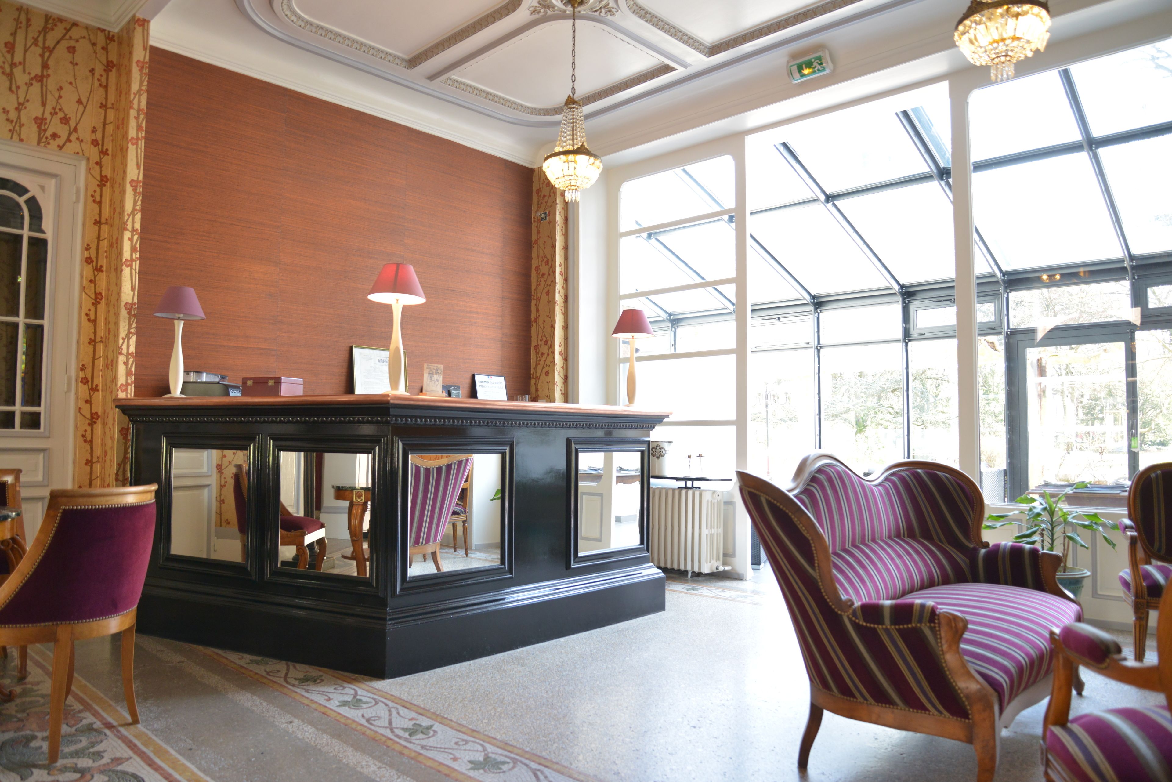 A lobby with a black console table, striped armchairs, and a large window with a view of greenery.