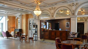 A lobby with ornate ceiling, a reception desk, and seating areas.