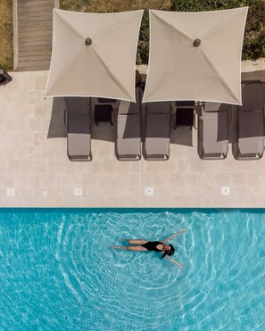 Una piscina al aire libre de temporada, sombrillas, tumbonas