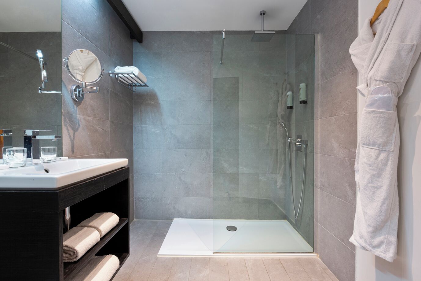 A modern bathroom with a glass-enclosed shower, a vanity with a mirror, and a towel rack.