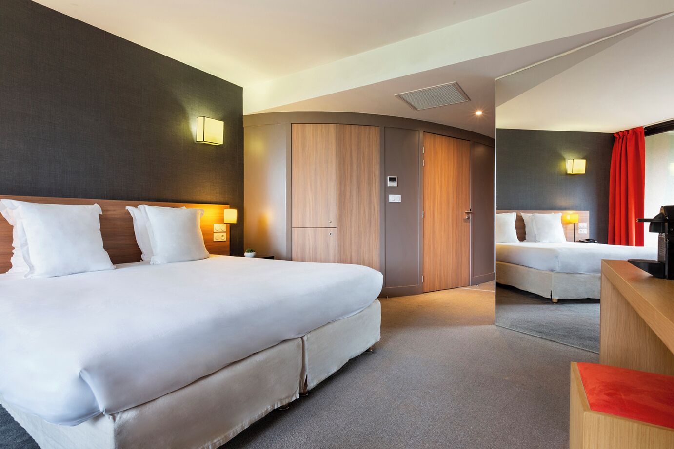 Une chambre d’hôtel avec un grand lit, un lit plus petit, un bureau et une armoire.