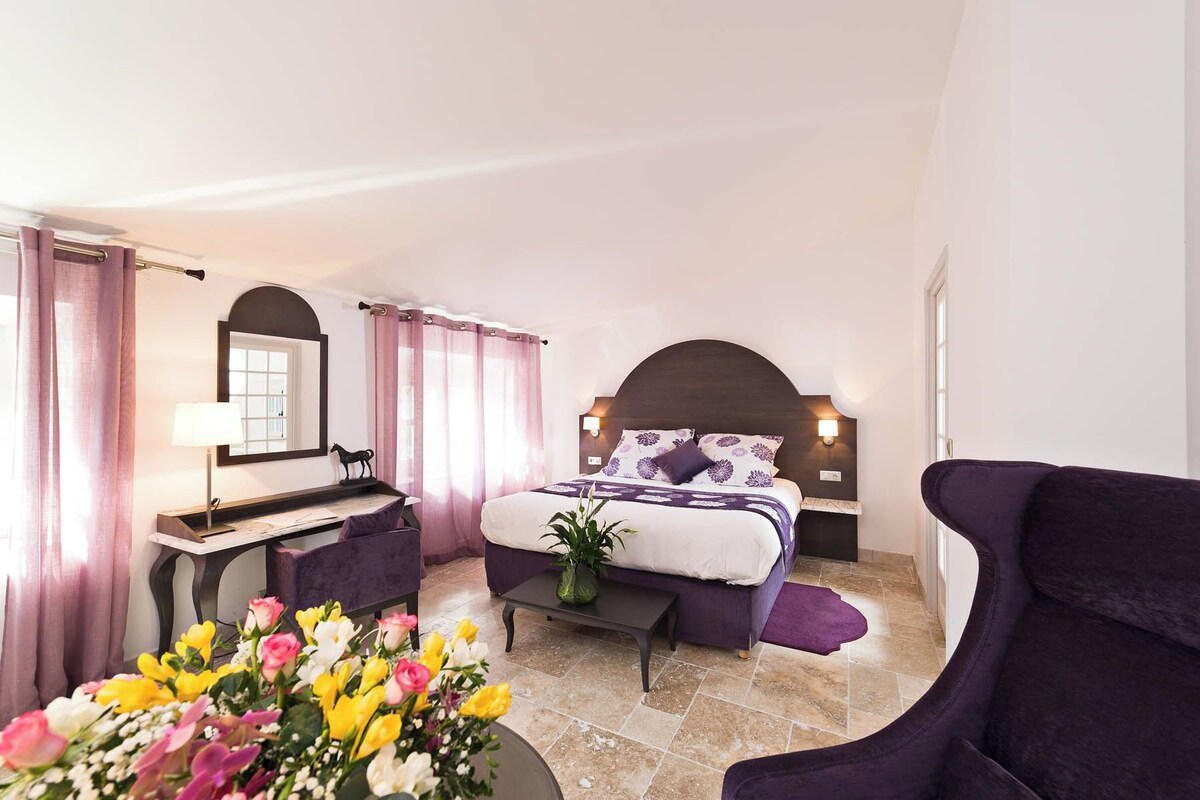 A bedroom with a bed, a desk, a chair, and a potted plant.