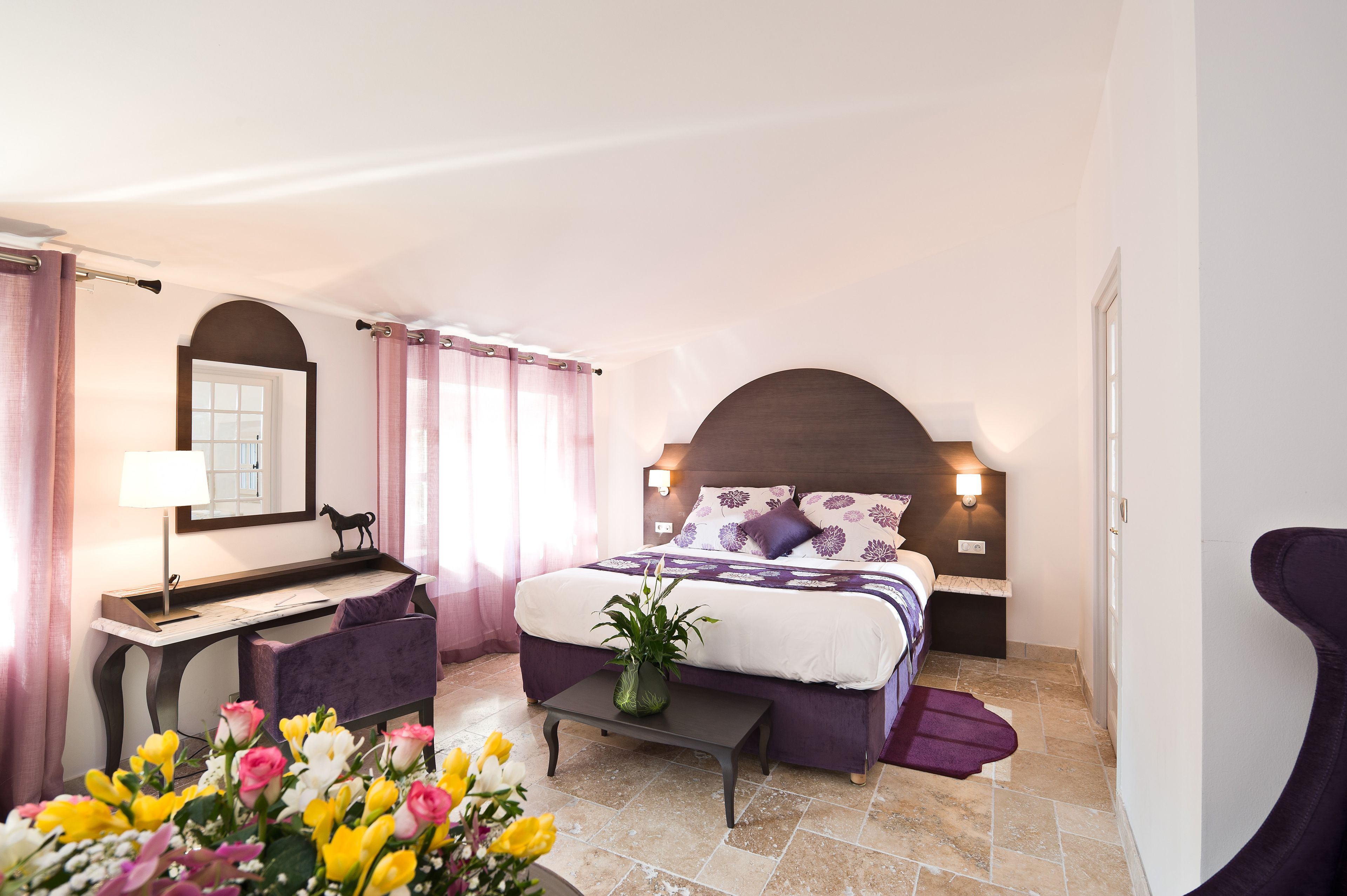 Un dormitorio con cama, escritorio, silla, mesita de noche y mesilla auxiliar.