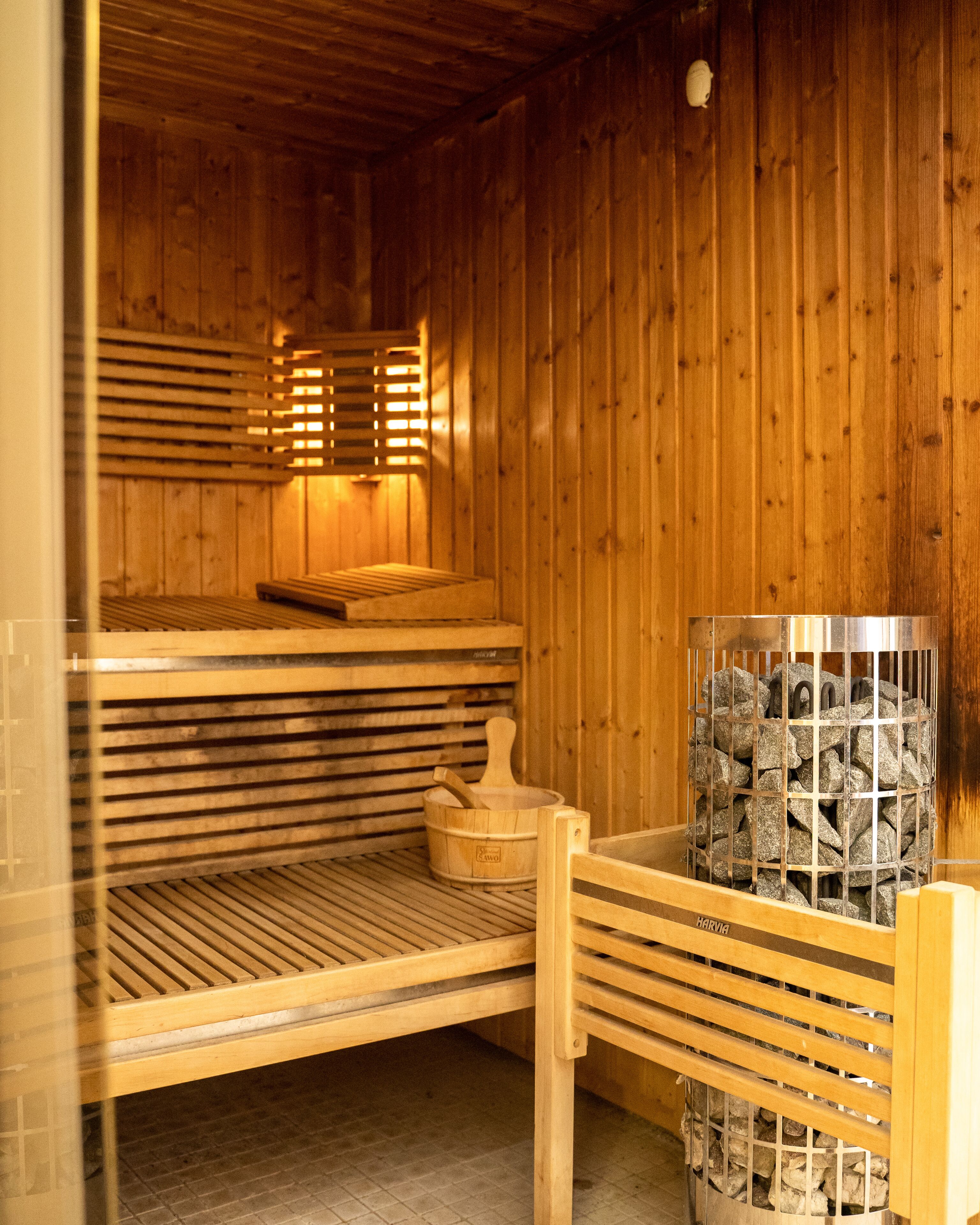 Een houten sauna met banken en een baksteen gevulde container.