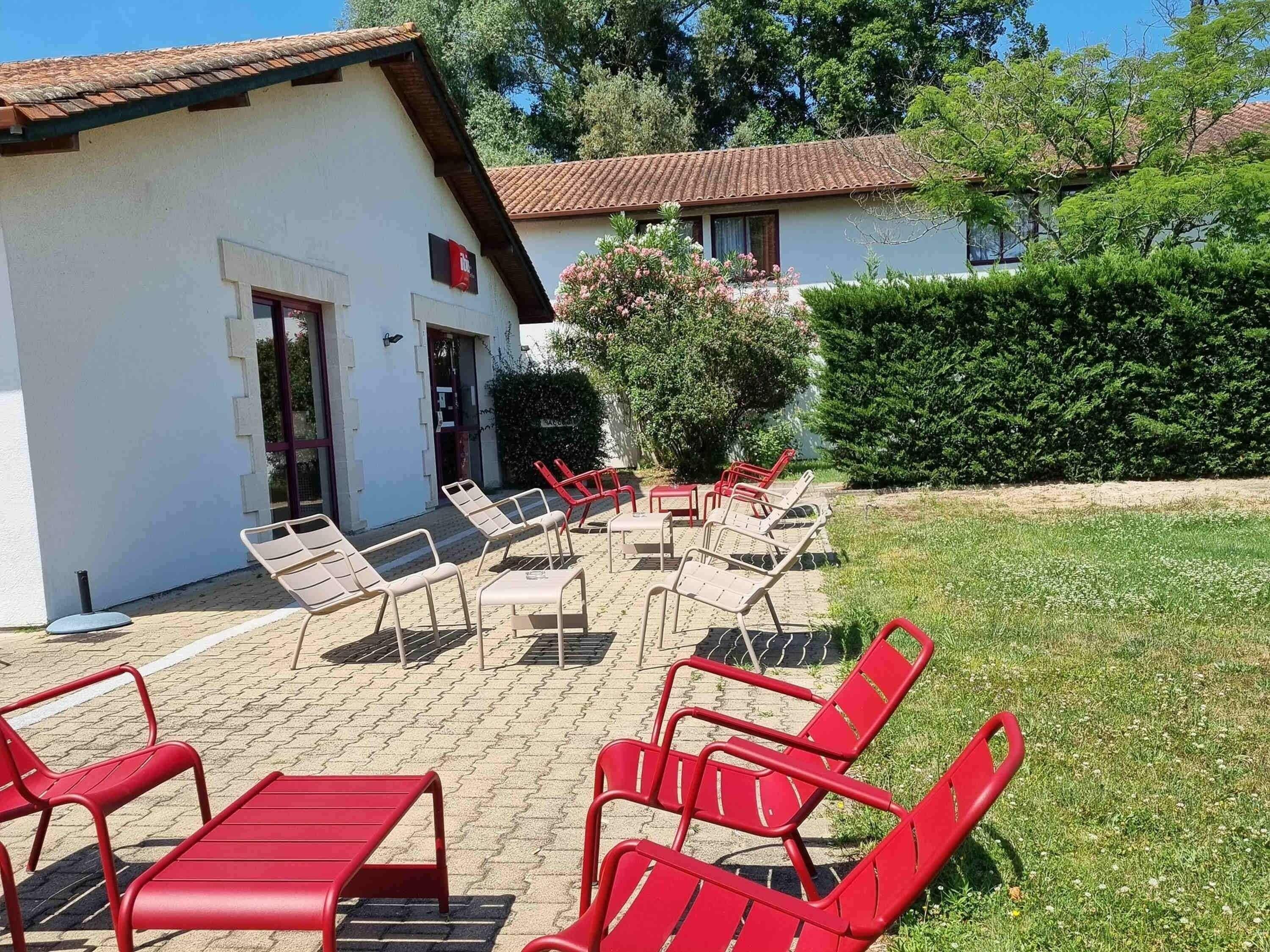 A building with a tiled roof, a door, and a window. There are outdoor chairs and a table.