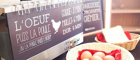 A kitchen counter with a sign indicating cooking times for different meats, a basket of eggs, and a shelf with kitchenware.