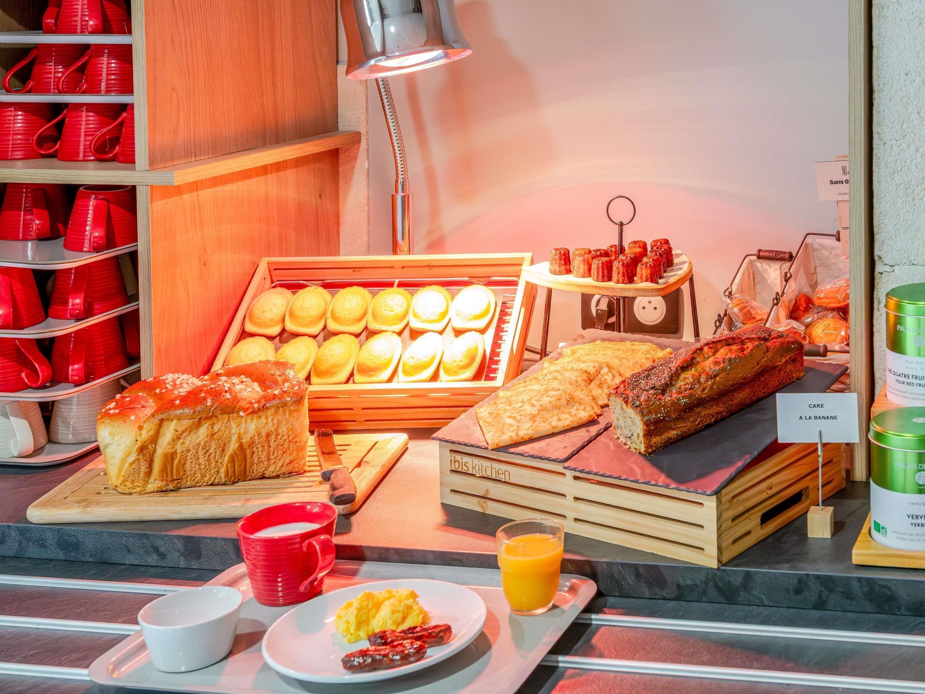 A breakfast buffet with various breads, pastries, and a juice glass.