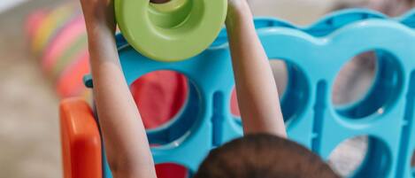 A child holding a green object above a blue chair with circular cutouts.