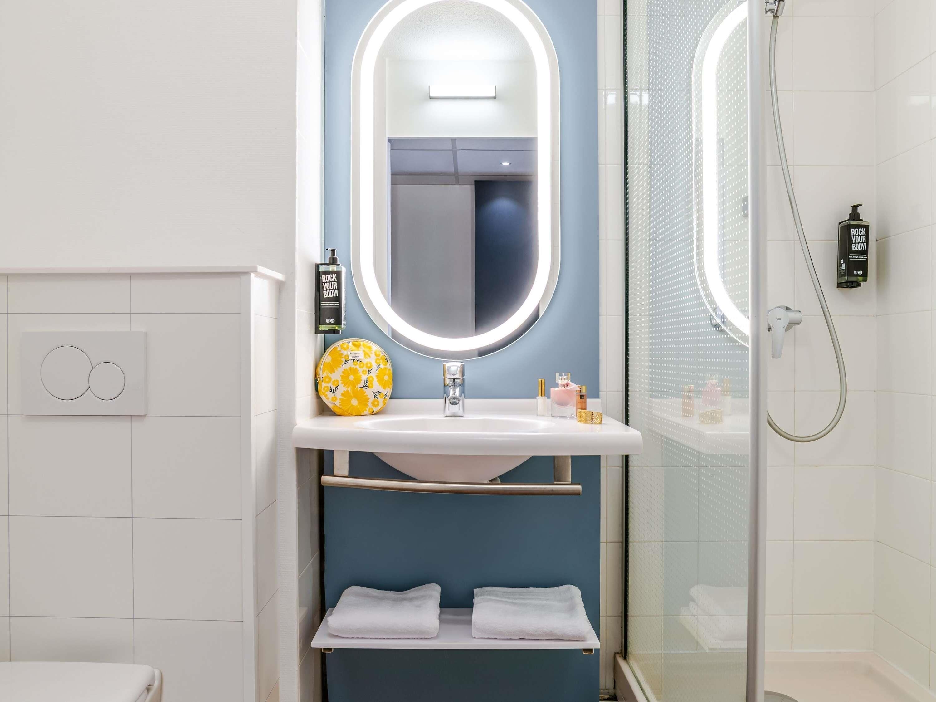 A bathroom with a white sink, a mirror, a towel rack, and a shower area.