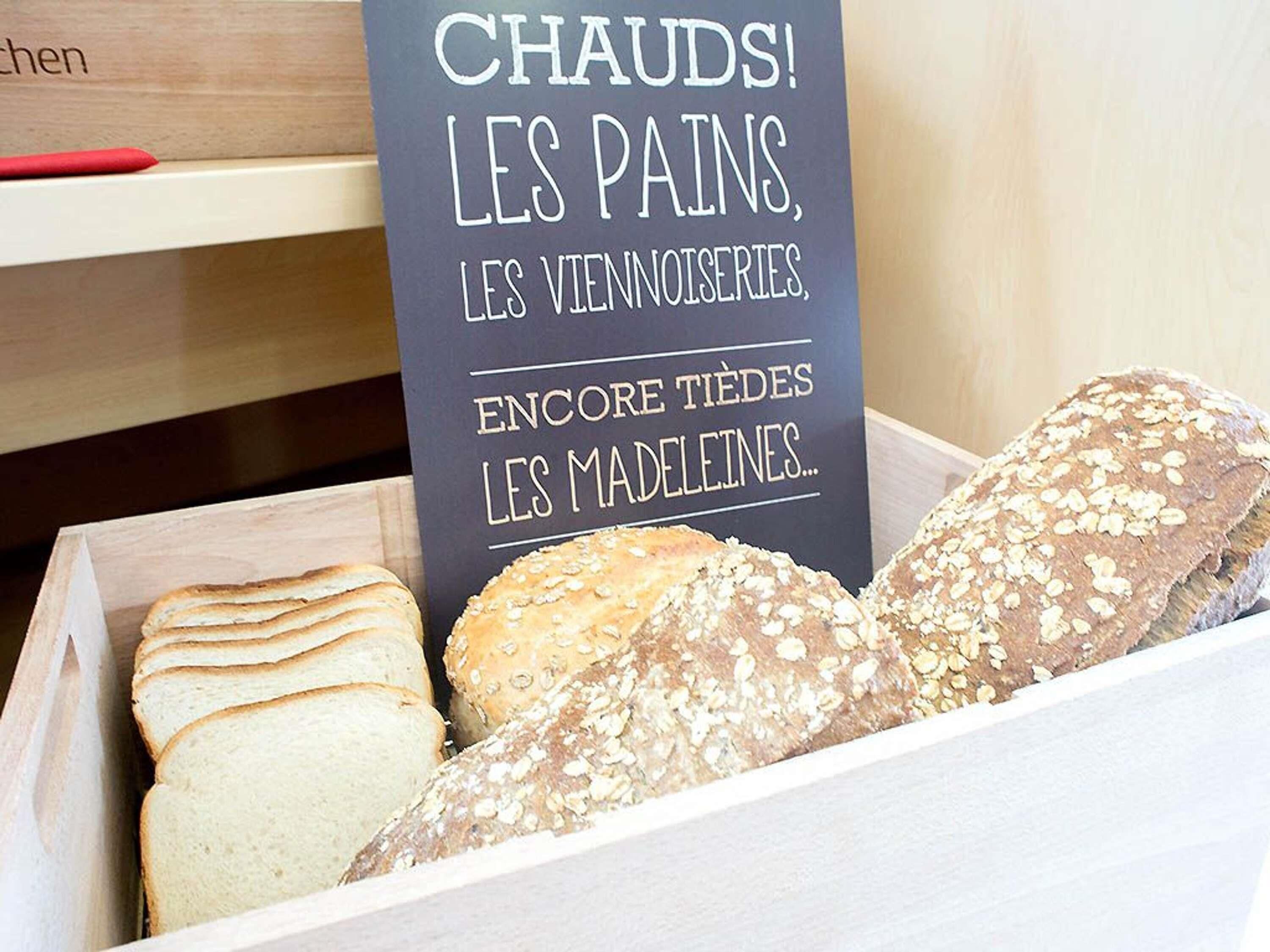 Una caja de madera con diferentes tipos de pan, y un cartel encima.
