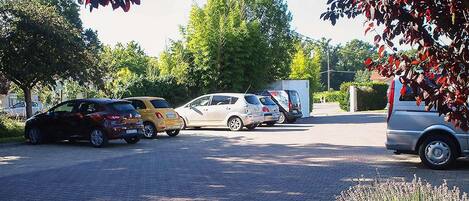 A parking lot with several cars and a truck, surrounded by trees and greenery.