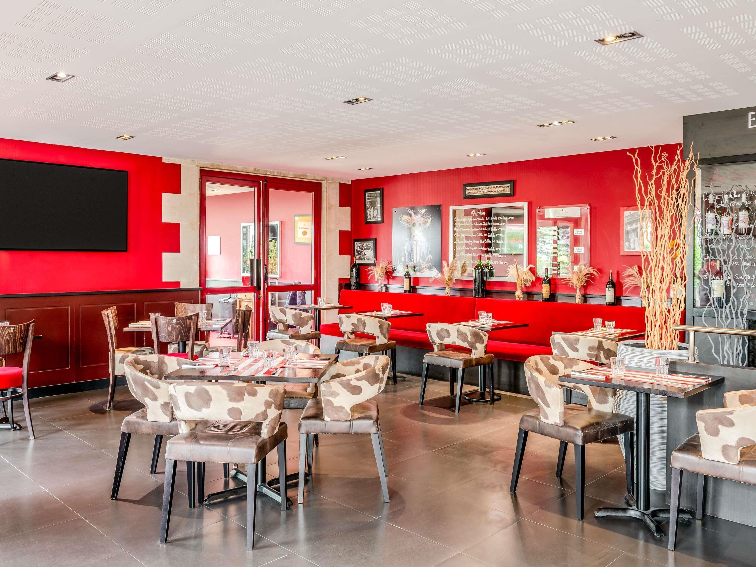 A restaurant interior with red walls, multiple seating areas, and a bar counter.