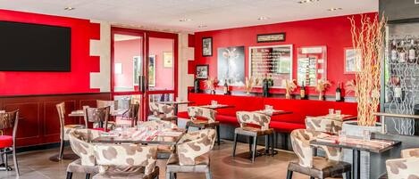 Un interior de restaurante con paredes rojas, varias zonas de estar y una barra.