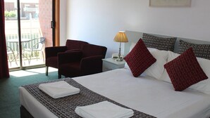 A hotel room with a bed, a chair, a lamp, and a view of the outside. - Hume Villa Motor Inn (Fawkner)