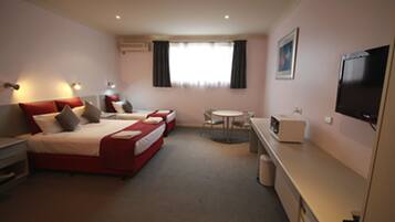 A hotel room with two beds, a small table, a TV, and a microwave.