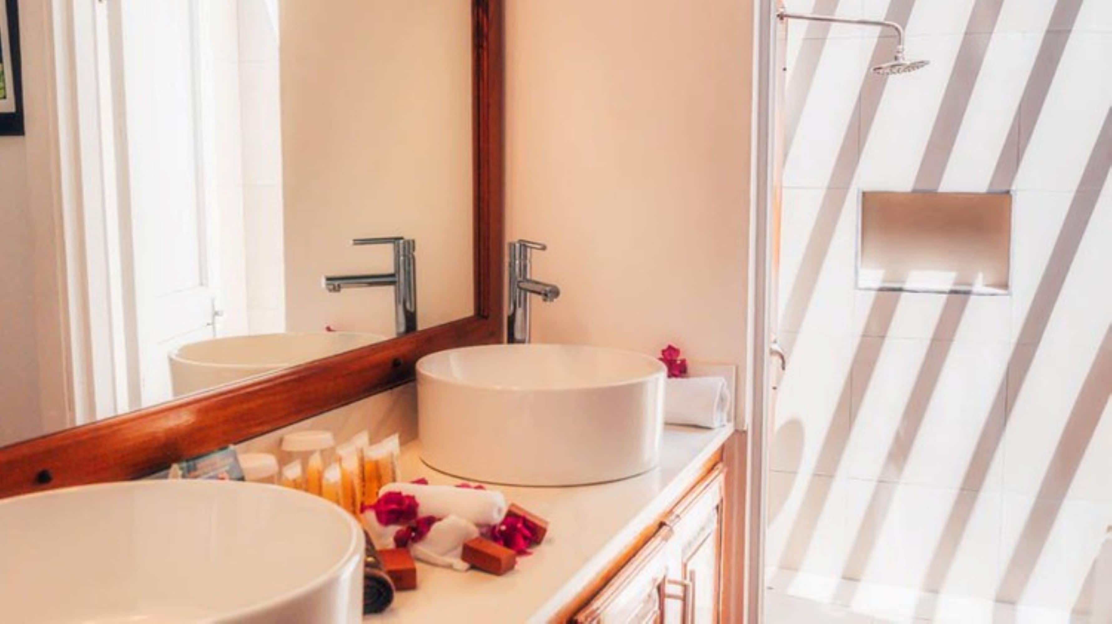 Un baño con dos lavamanos, un espejo y una zona de ducha.