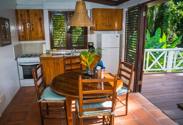 A wooden dining table with chairs, a kitchen with wooden cabinets, a stove, and a refrigerator.