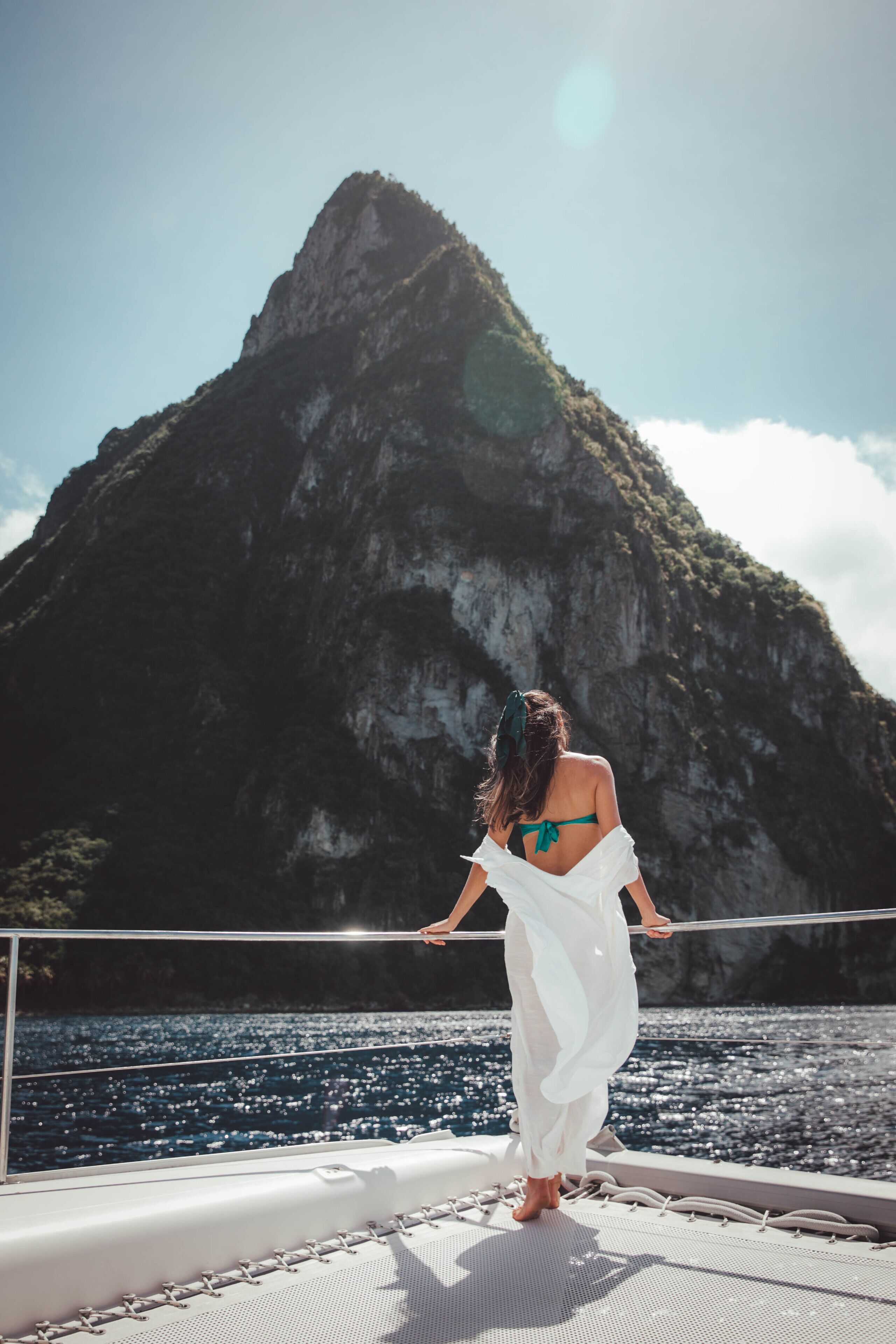 A person standing on a boat deck with a mountainous backdrop.