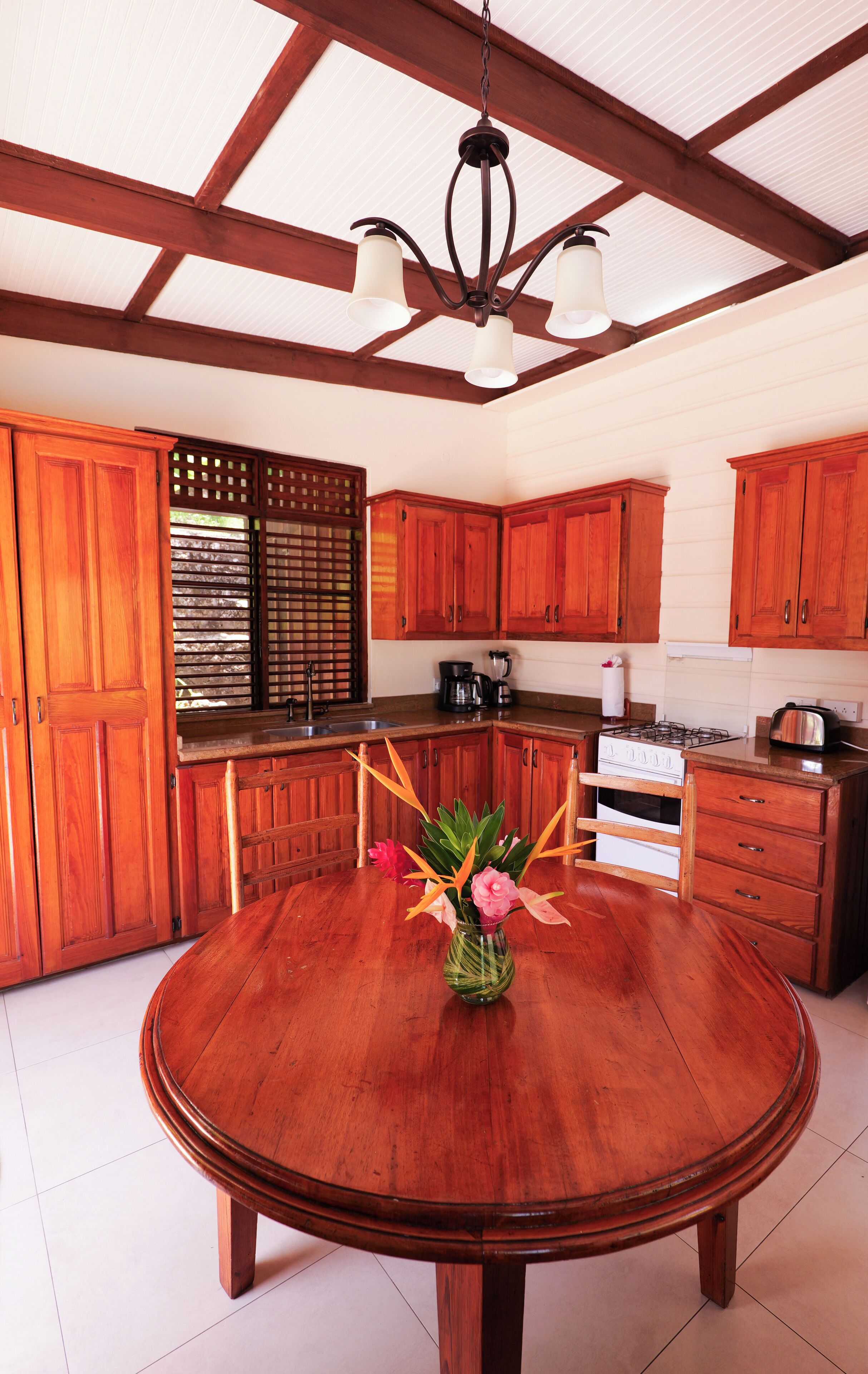 A spacious kitchen with wooden cabinets, a central island, and a hanging light fixture.