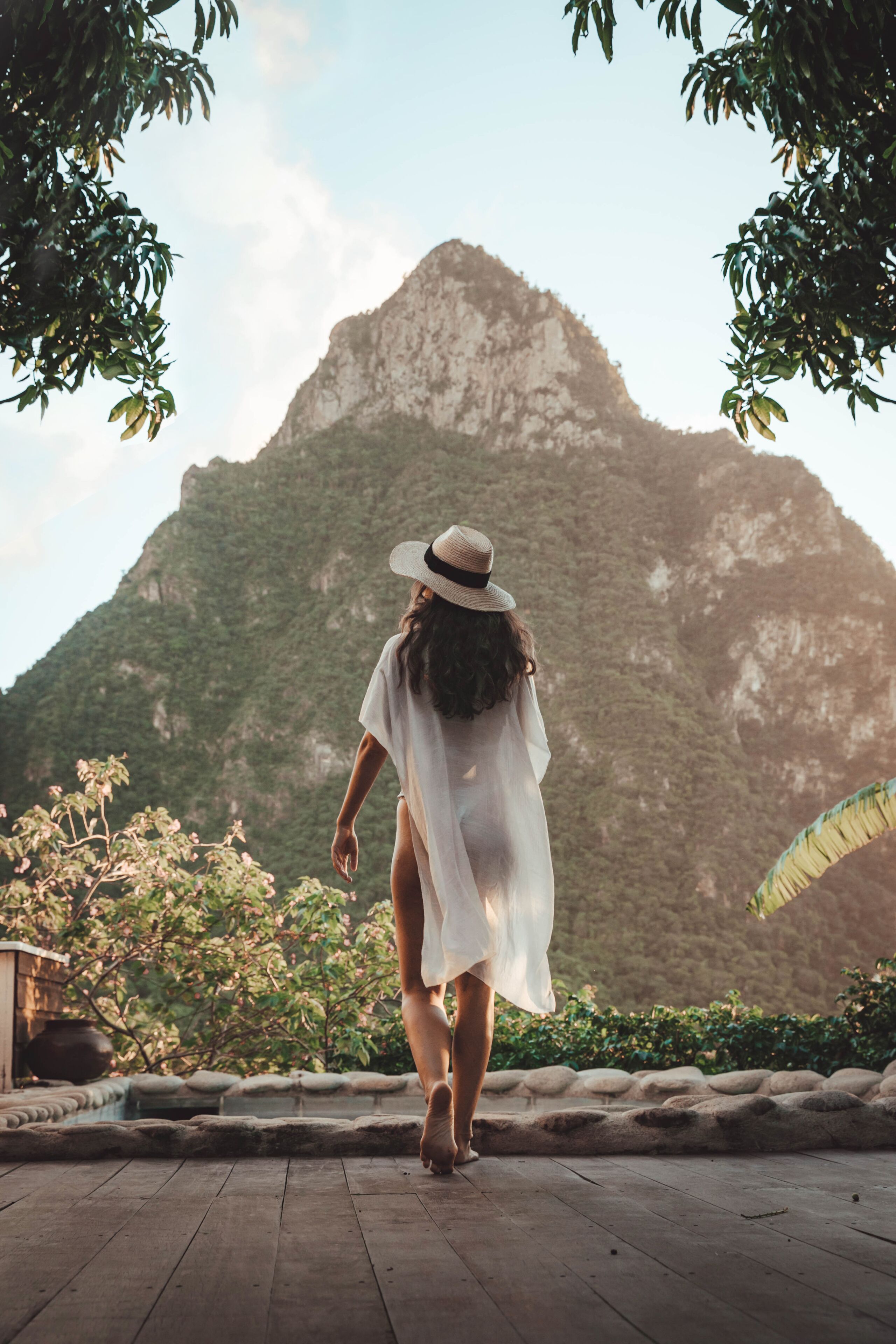 A person walking on a wooden deck with a mountainous backdrop.