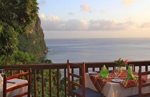 A table set for dining with a view of the ocean and a cliff. - Stonefield Villa Resort (Soufrière)