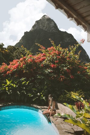 A person sitting by a pool with a mountain in the background. - Stonefield Villa Resort (Soufrière)