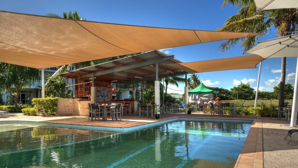 A swimming pool with a covered seating area, a bar, and outdoor seating with umbrellas. - The Terraces Apartments Resort (Nadi)