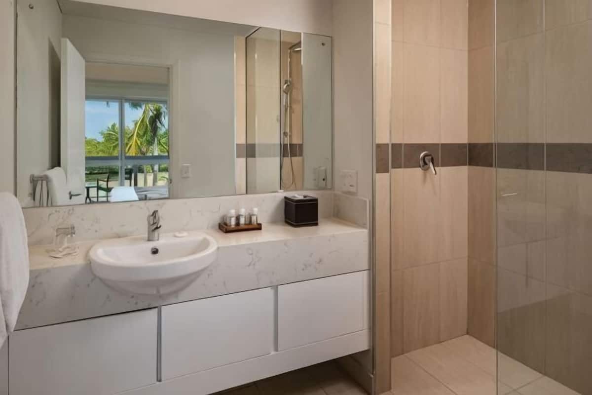 A bathroom with a white sink, mirror, and shower.
