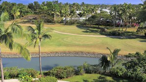 A golf course with a pond, palm trees, and a view of distant mountains. - The Terraces Apartments Resort (Nadi)