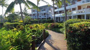 A resort with a wooden pathway leading to a building with multiple balconies, surrounded by lush greenery and palm trees. - The Terraces Apartments Resort (Nadi)